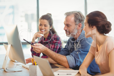 Team of graphic designers discussing over computer at desk