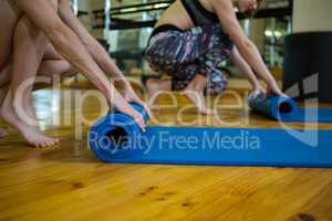 Fit women rolling up exercise mats after workout