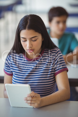 Schoolgirl using digital tablet in classroom