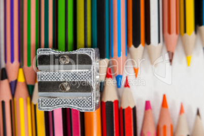 Colored pencils and sharpener on white background