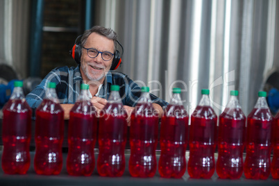 Male factory worker monitoring cold drink bottles