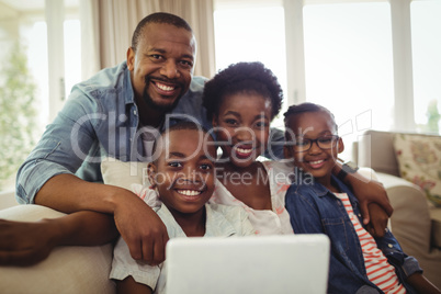 Portrait of parents and son sitting on sofa in living room