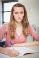 Portrait of schoolgirl doing homework in classroom