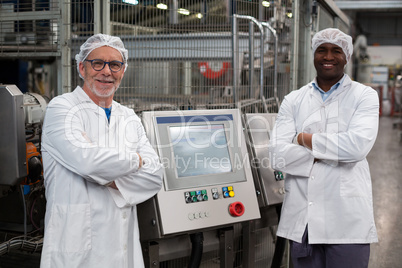 Portrait of two factory engineers standing with arms crossed