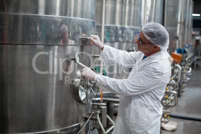 Factory engineer monitoring a pressure gauge of storage tank