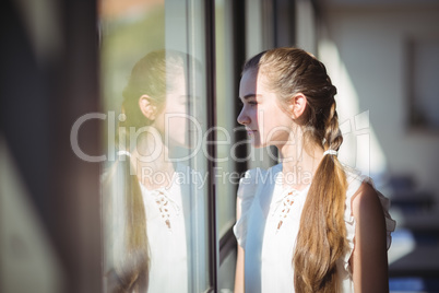 Schoolgirl looking through window in classroom