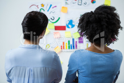 Female graphic designers looking at the white board