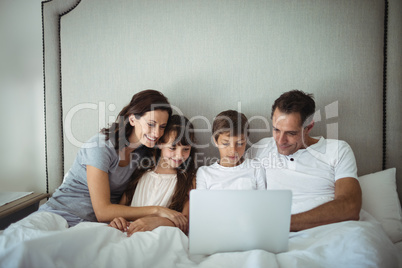 Parents and kids using laptop in bed