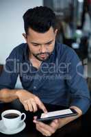 Business executive using digital tablet while having cup of tea