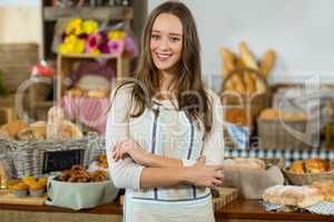 Portrait of female staff standing with arms crossed at counter