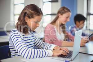 Students using digital tablet and laptop in classroom