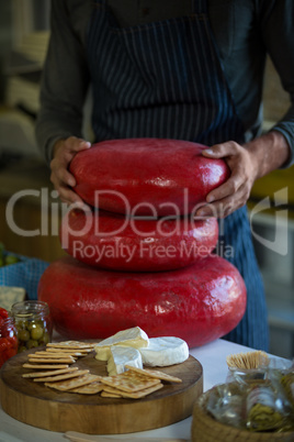 Mid section of salesman holding stacked gouda cheese