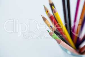 Colored pencils kept in glass on white background