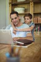 Father and son using laptop in study room