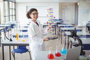 Portrait of happy schoolgirl experimenting molecule model in laboratory