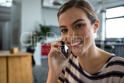 Smiling female graphic designer talking on mobile phone