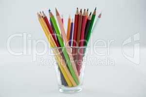 Colored pencils kept in glass on white background