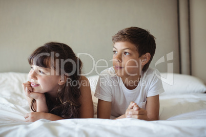 Siblings looking away in bed