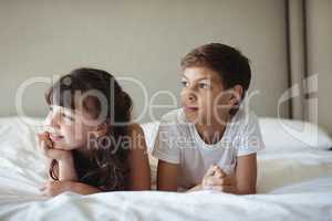 Siblings looking away in bed