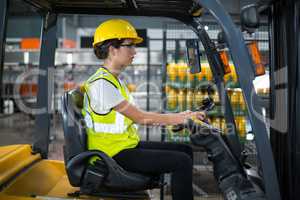 Female factory worker driving forklift