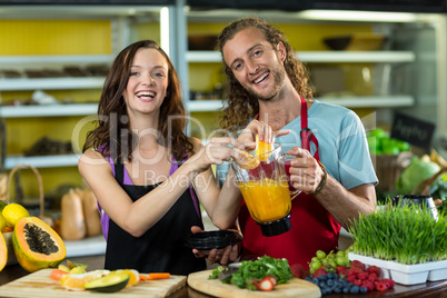 Smiling shop assistant preparing juice at health grocery shop