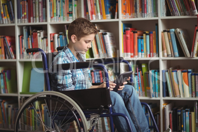Disabled schoolboy using digital tablet in library