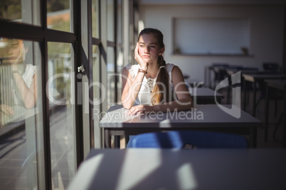 Thoughtful schoolgirl sitting in classroom