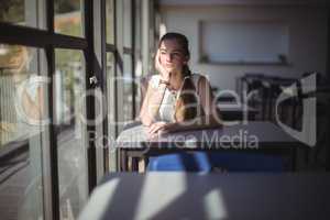 Thoughtful schoolgirl sitting in classroom