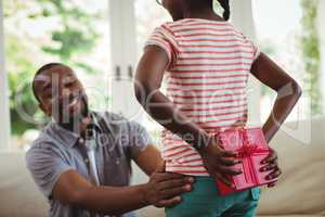 Daughter hiding gift behind her back for father