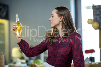 Shop assistant looking at olive oil bottle