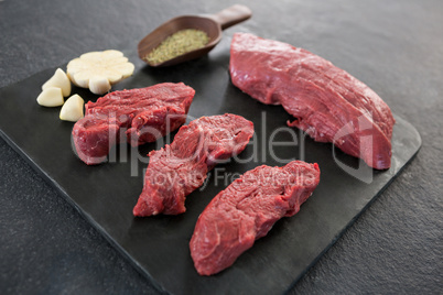 Beef steaks, spices and garlic on slate plate