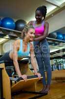 Trainer assisting woman with wunda chair in fitness studio