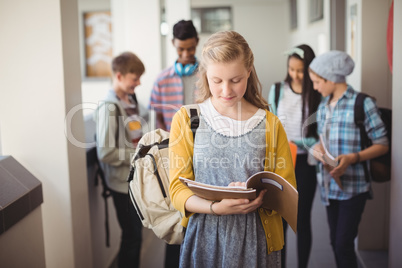 Schoolgirl standing in corridor reading notebook