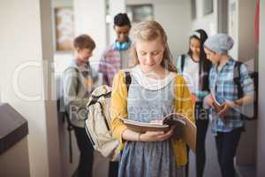 Schoolgirl standing in corridor reading notebook