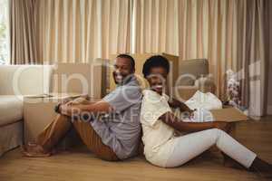 Portrait of couple sitting back to back in living room