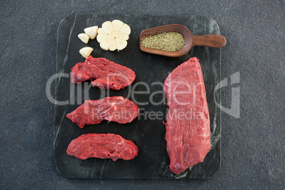 Beef steaks, spices and garlic on slate plate