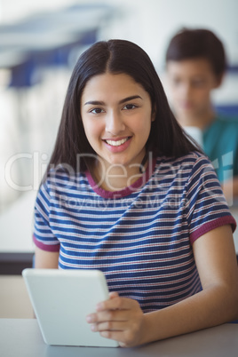 Portrait of schoolgirl using digital tablet in classroom