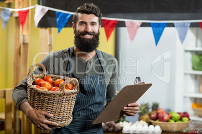 Vendor holding a clipboard and a basket of tomatoes at the grocery store