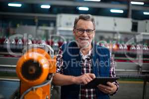 Portrait of smiling factory worker standing with a digital tablet in the factory