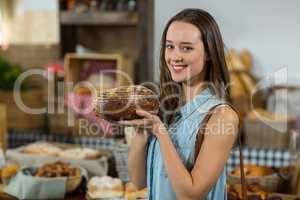 Portrait of smiling female customer holding a round loaf of bread at counter