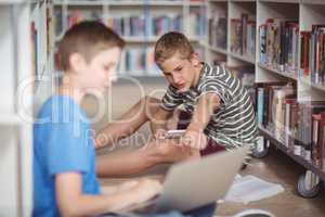 Attentive schoolboys studying in library