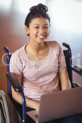 Portrait of disabled schoolgirl using laptop in campus