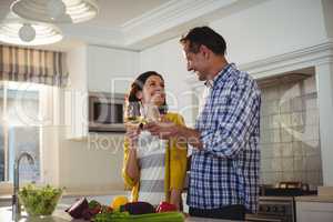 Happy couple toasting glasses of wine in kitchen
