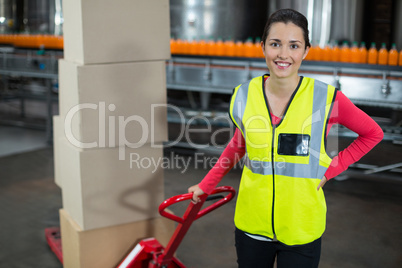 Female factory worker holding trolley of cardboard boxes