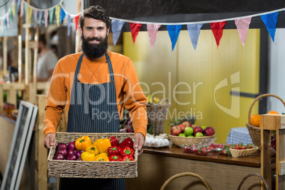 Vendor holding a basket of onion and bell pepper at the grocery store