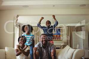 Parents and kids having fun while watching television in living room