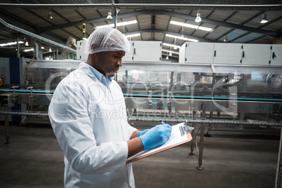 Factory engineer maintaining record on clipboard in factory