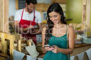 Smiling woman using mobile phone at counter