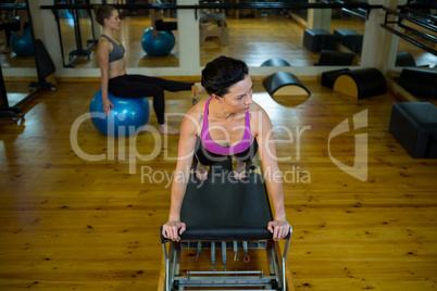 Determined woman practicing stretching exercise on reformer