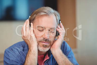 Male graphic designer listening music on headphones